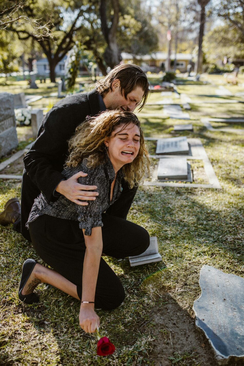 A woman crying besides a man on a cemetery