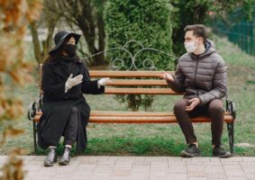 A man and a woman seated apart on an bench during the COVID pandemic