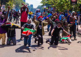 A group of Youths with holding the national flag with some kneeling down in Surrender and some raising arms crossed as a sign of peace amidst the June protest against the finance bill 2024